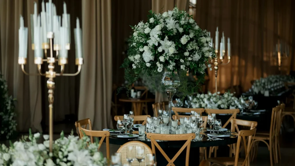 Luxurious wedding reception setup featuring elegant floral arrangements and candlelit tables in a sophisticated indoor venue.
