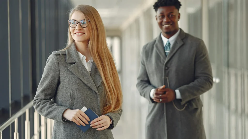 Professionals smiling in an airport terminal, ready for business travel.