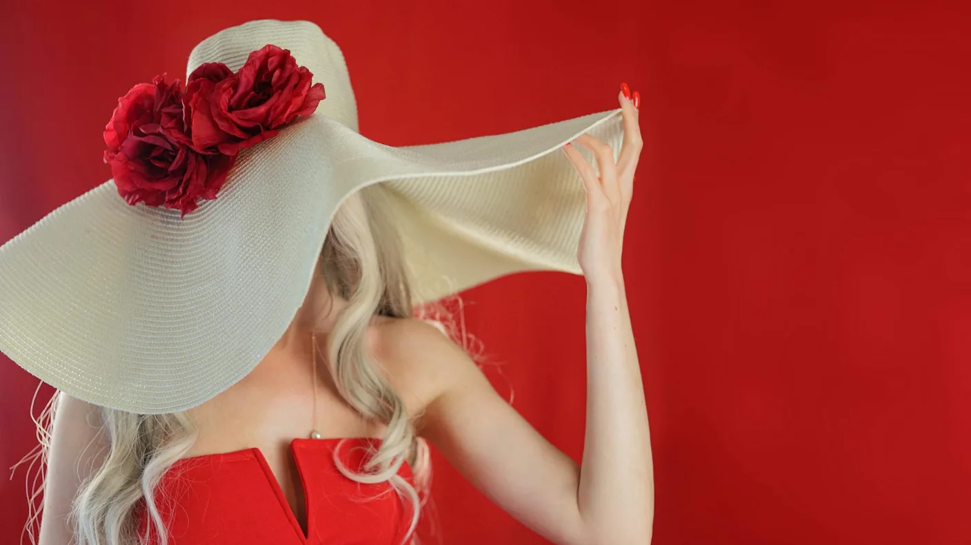 Woman in red dress with wide-brimmed hat adorned with roses, quintessential Kentucky Derby fashion