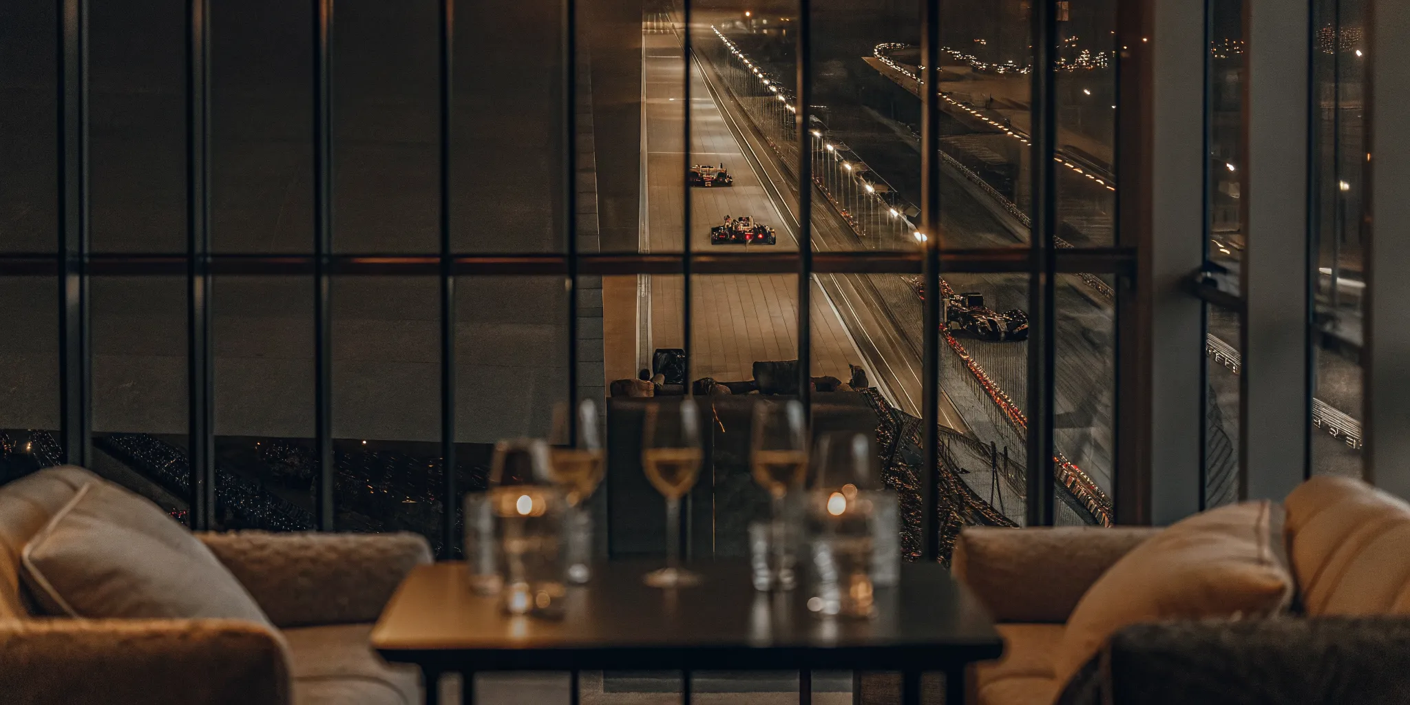 Formula 1 cars racing at Yas Marina Circuit under the track lights with VIP suites in background